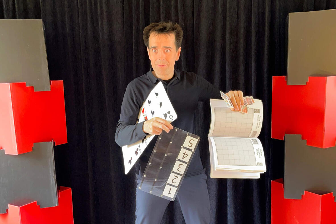 Monsieur Fred réalise une prédiction mentaliste avec des cartes et un album à timbres lors d’un spectacle interactif pour enfants et familles.