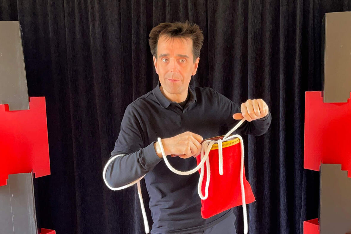 Monsieur Fred réalise un tour de magie où une corde est coupée puis raccommodée sous les yeux étonnés du public lors du spectacle.