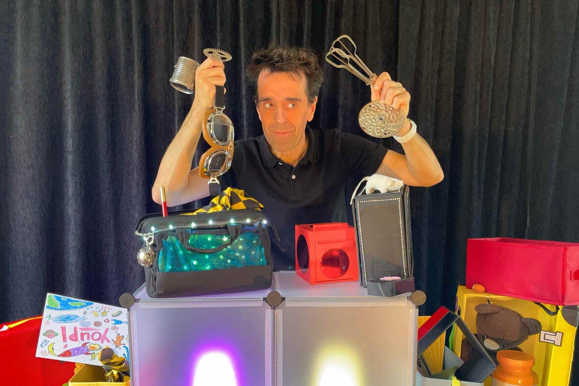 Photo de Monsieur Fred en pleine représentation, entouré de souvenirs et de surprises pour les enfants lors du spectacle “Zouick, fouick, touick”.