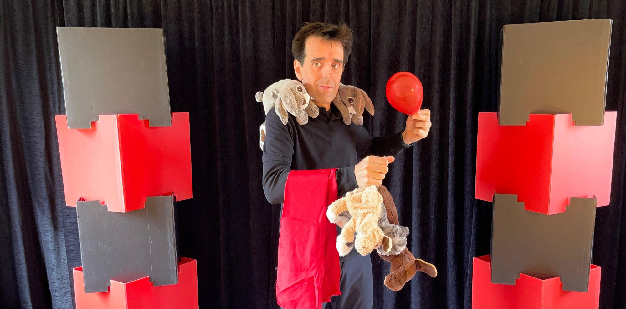 Spik Spakkk ! Monsieur Fred fait apparaître un lapin en peluche à partir d’un foulard, entouré de ballons rouges, lors d’un numéro de magie pour enfants
